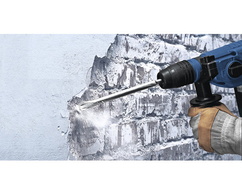 Ein Arbeiter nutzt einen Abbruchhammer, um eine Wand zu bearbeiten.