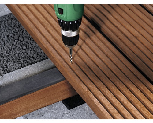 Eine Bohrmaschine bohrt in eine Holzterrasse.