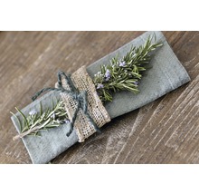 Dekorative Stoffserviette mit Rosmarinzweig und Juteseil auf einem Holztisch.