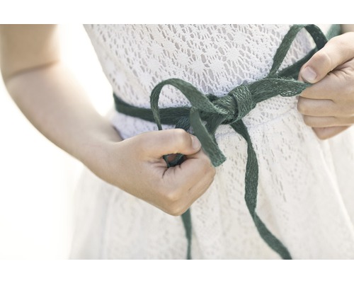 Frau bindet Schleife an einem weißen Kleid