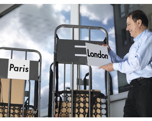 "Mann hält Schild mit der Aufschrift London vor einen Transportwagen