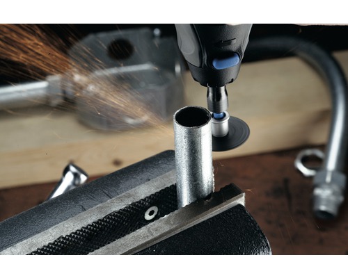 Eine Rohrzange hält ein Rohr während ein Multifunktionswerkzeug es bearbeitet und Funken sprühen.