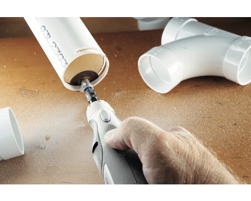 Eine Person schneidet ein Kunststoffrohr mit einem Multifunktionswerkzeug.