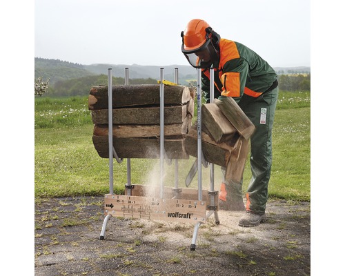 Eine Person mit Schutzkleidung schneidet Holz mit einer Kettensäge auf einem Holzsägebock von Wolfcraft
