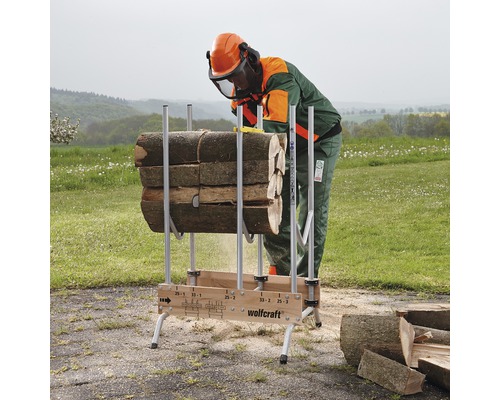 Eine Person mit Schutzausrüstung sägt Holz auf einem Wolfcraft Sägebock.