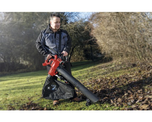 Mann benutzt einen Elektro-Laubsauger im Garten, um Laub zu entfernen.