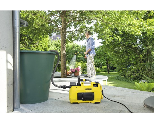 Garten mit Regentonne, Hauswasserwerk und Person beim Bewässern von Pflanzen