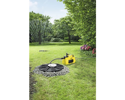 Garten mit Rasen, Bäumen, Blumen, Regner und gelber Gartenpumpe mit Bewässerungssystem