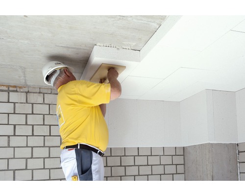 Handwerker montiert Dämmplatten an der Decke mit einem Reibebrett für Wärmedämmung.