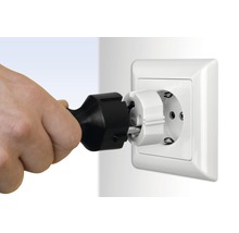 Eine Hand steckt einen Schutzkontaktstecker in eine Steckdose mit Kindersicherung.