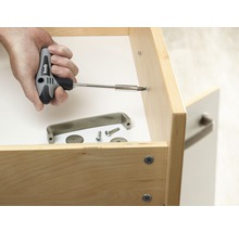 Hand schraubt Möbelgriff mit Schraubendreher an Schublade