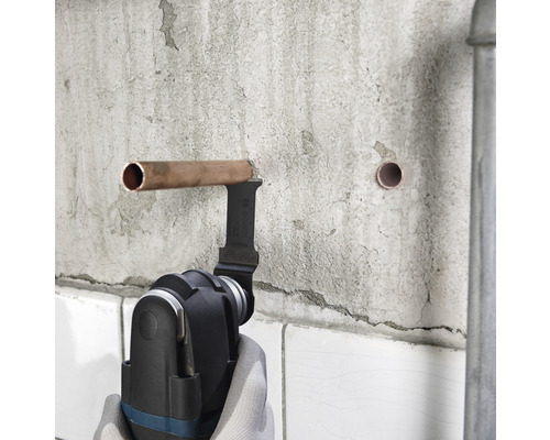 Multifunktionswerkzeug schneidet Kupferrohr an einer Wand