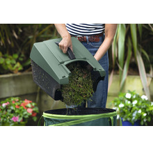 Gartenarbeitskraft leert Grasschnitt in einen Gartensack