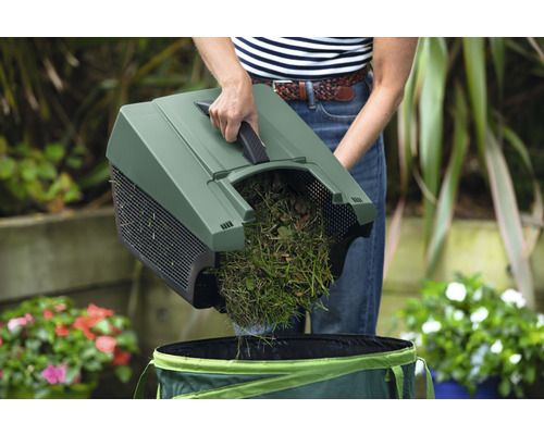 Gartenarbeitskraft leert Grasschnitt in einen Gartensack
