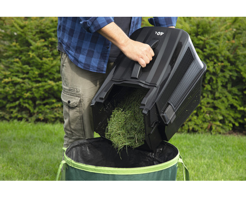 Eine Person leert einen 40-Liter-Grasfangkorb in einen Gartensack.