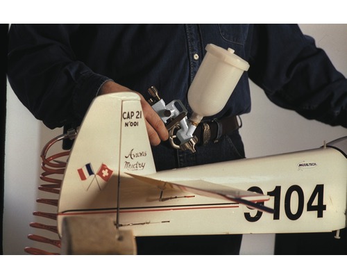 Person hält Spritzpistole über ein Modellflugzeug