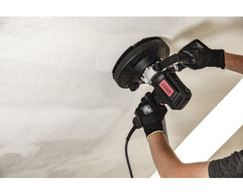 Ein Mann schleift eine Decke mit einem Deckenschleifer.