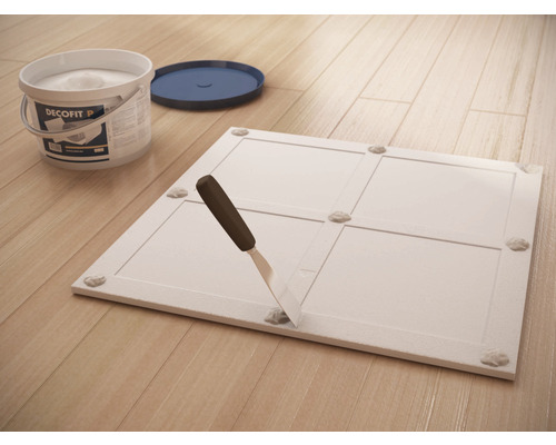 Montagekleber, Spachtel und Platte auf Holzboden