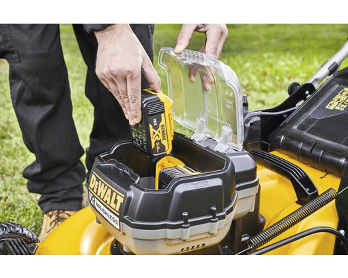 Eine Person setzt einen DeWalt 18 Volt 5.0 Ah Akku in einen Rasenmäher ein.