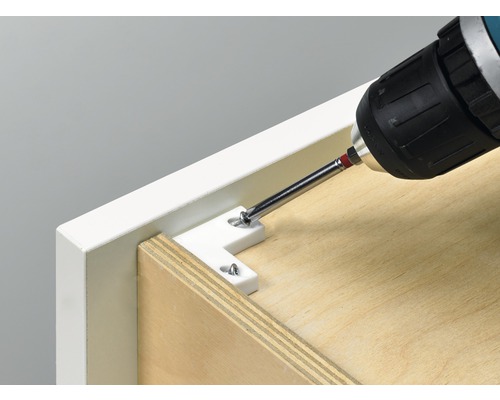 Ein Akkuschrauber befestigt einen Winkelverbinder an einem Möbelstück.