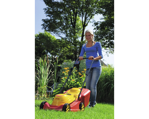 Eine Frau bedient einen Rasenmäher im Garten.