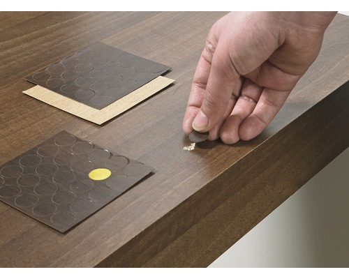 Reparaturaufkleber werden auf eine beschädigte Holzoberfläche aufgebracht.