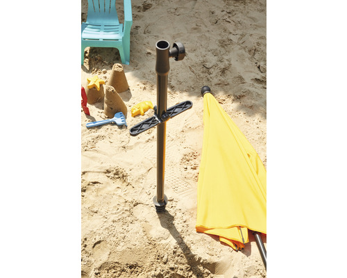Sandszene mit Sonnenschirmständer, Spielzeug und Liegestuhl im Sand