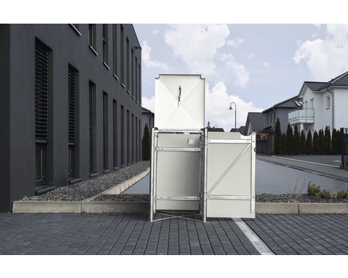Mülltonnenbox mit geöffnetem Deckel vor einem Wohnhaus
