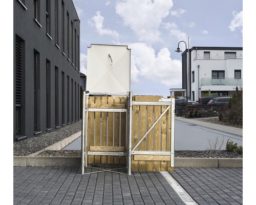 Mülltonnenbox mit Rahmen und Holztür vor Wohnhaus