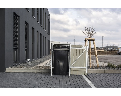 Mülltonnenbox aus Metall und Holz mit schwarzer Mülltonne vor Gebäude