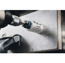 Bohrmaschine mit Bosch Lochsäge beim Bohren eines Lochs in ein Material