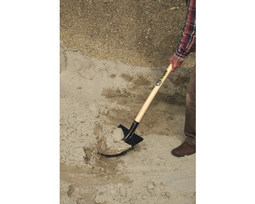 Eine Schaufel hebt Sand auf.