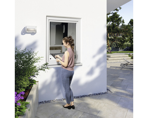 Frau steht vor Fenster mit Fensterbank und Tablet