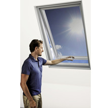 Ein Mann öffnet ein Dachfenster und blickt in den blauen Himmel.