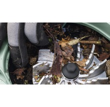 Nahaufnahme des Schneidwerks eines Gartenhäckslers mit Gartenhandschuhen und Blättern