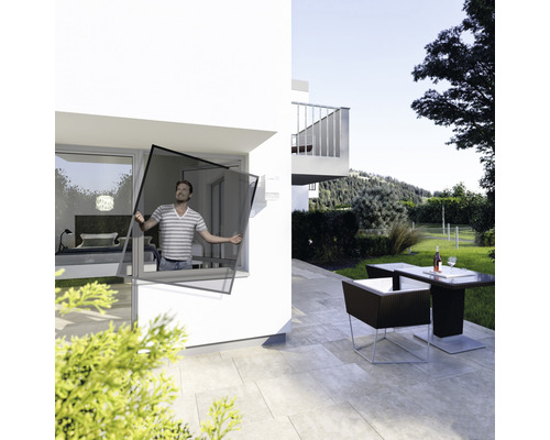 Mann montiert einen Insektenschutzrahmen an einem Fenster eines modernen Hauses