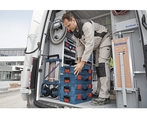 Handwerker im Lieferwagen verstaut Werkzeugkoffer und Sortimo Werkzeugwagen