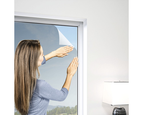 Frau bringt Sichtschutzfolie am Fenster an