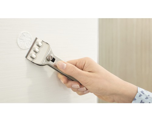 Eine Hand hält einen Glasschaber, um Rückstände von einer Oberfläche zu entfernen.