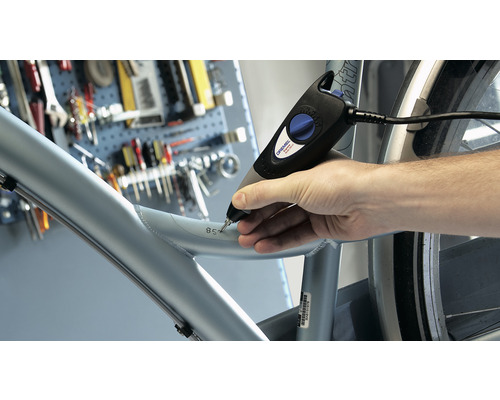 Ein Mann benutzt ein Graviergerät, um eine Zahl in einen Fahrradrahmen zu gravieren.