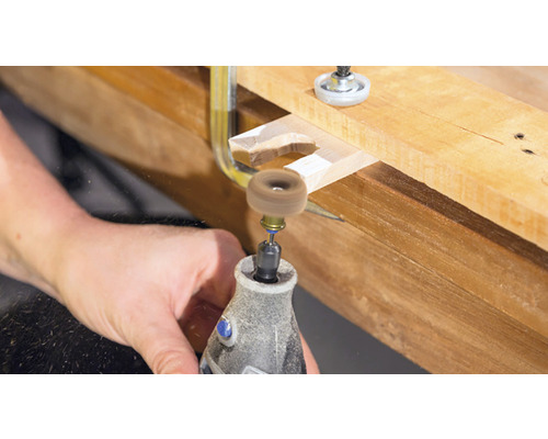 Dremel Werkzeug beim Bearbeiten eines Holzstücks mit einer Schleifscheibe.