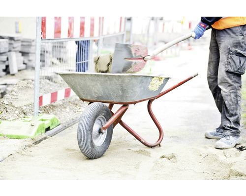 Bauarbeiter befüllt Schubkarre mit Schaufel auf Baustelle