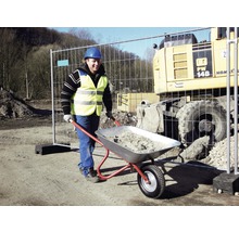 Bauarbeiter schiebt Schubkarre mit Material auf einer Baustelle.
