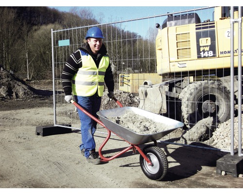 Bauarbeiter schiebt Schubkarre mit Material auf einer Baustelle.