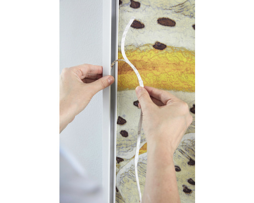 Person befestigt eine Leinwand mit Klebeband in einem Bilderrahmen.