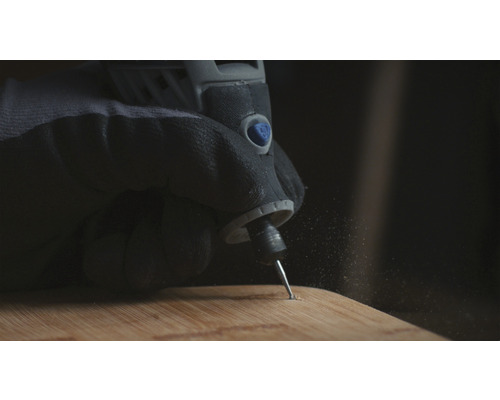 Hand mit Schutzhandschuh verwendet einen Multifunktionsschleifer auf einem Holzbrett.