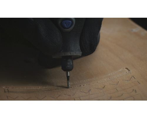 Eine Person verwendet ein Multifunktionswerkzeug zum Schnitzen in Holz.