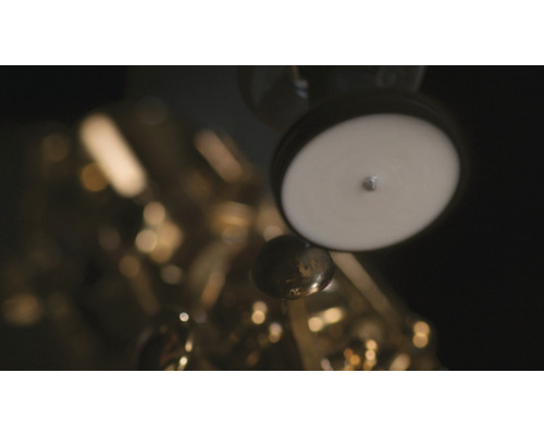 Detailaufnahme eines goldenen Saxophons mit weißen Polstern und Klappen