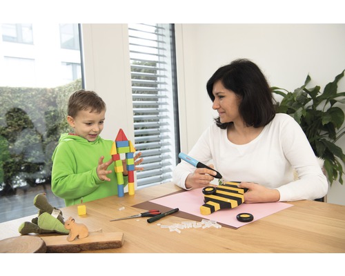 Frau und Kind basteln mit Heißklebepistole und Holz