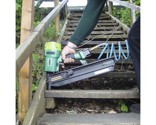 Eine Person benutzt einen Druckluftnagler auf einer Holztreppe.